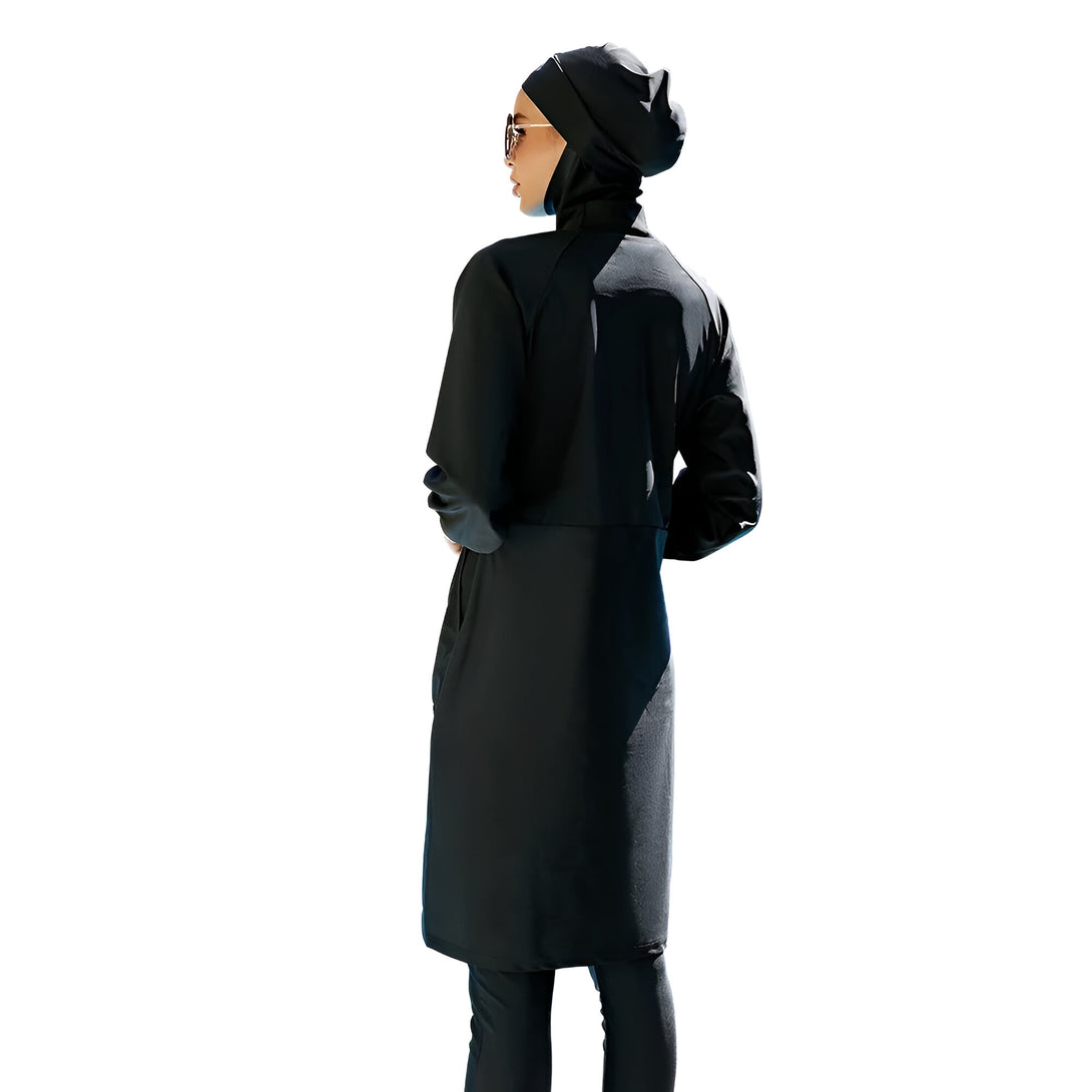 Une femme portant un maillot de bain musulman noir à manches longues et un hijab noir, vue de dos.