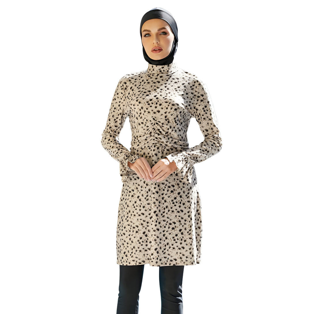 Une femme portant un hijab noir et une robe de bain musulmane à manches longues avec un motif floral beige et noir.