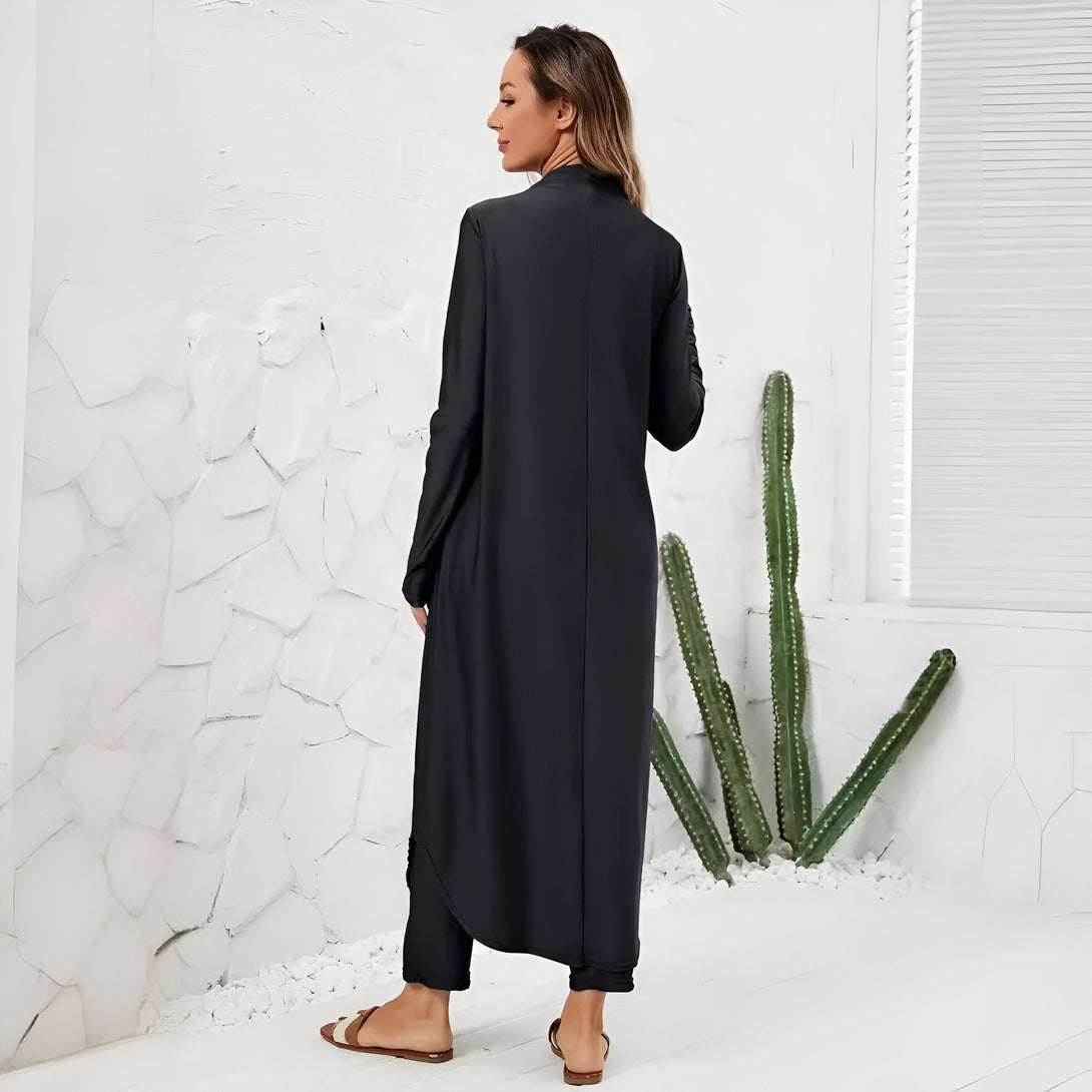 Une femme porte une longue robe noire élégante et ample, idéale pour les occasions spéciales. La robe est à manches longues et a une coupe fluide. Elle est parfaite pour un look chic et confortable.