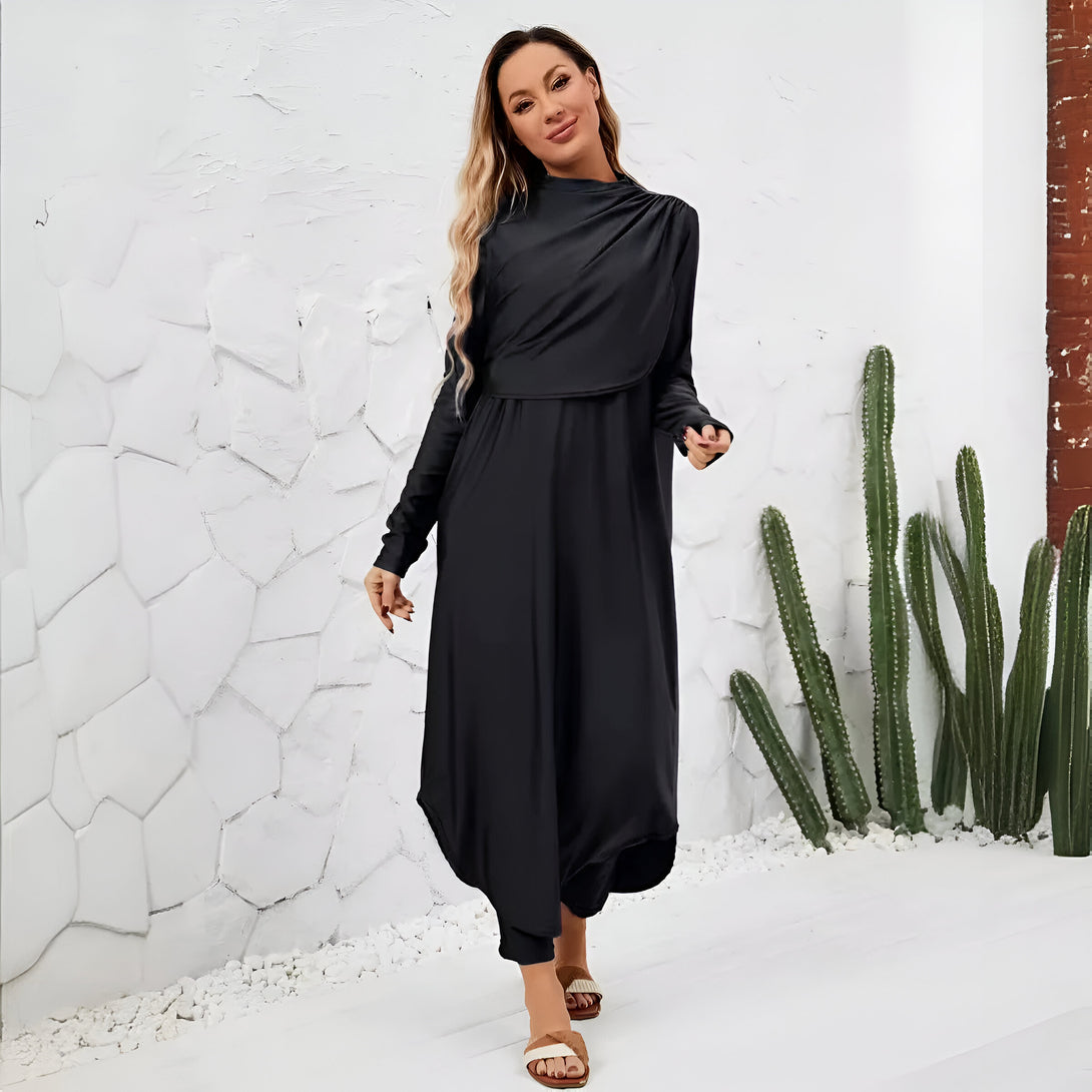Une femme porte une robe noire ample et élégante avec un col haut. La robe est parfaite pour les occasions spéciales ou pour un look décontracté chic.