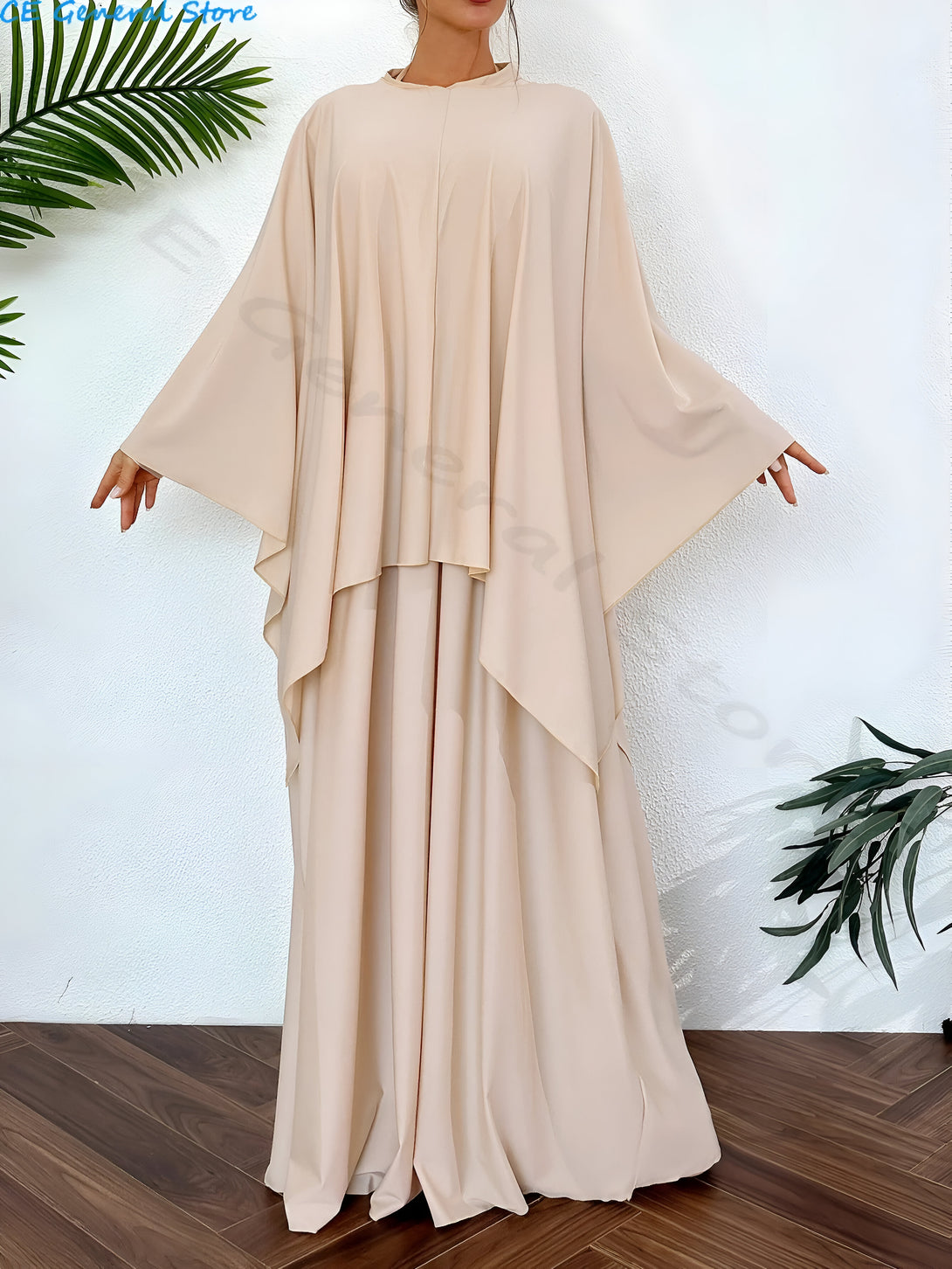 Une femme porte une longue robe beige à manches longues et un col rond. La robe est ample et fluide, et elle est parfaite pour les occasions spéciales.