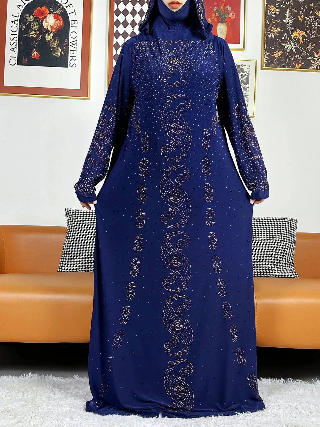 Une robe longue bleue marine à manches longues avec un motif de strass dorés. La robe est dotée d'une capuche et est parfaite pour les occasions spéciales.