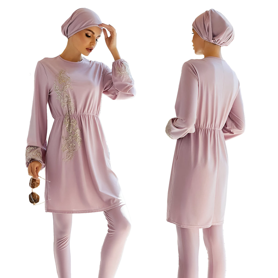 Une femme portant une tenue de bain islamique rose avec des détails dorés. La tenue comprend un haut à manches longues avec une ceinture élastique à la taille et un pantalon assorti.