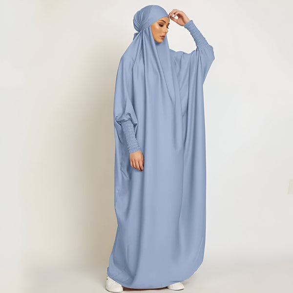 Une femme portant une abaya bleu clair avec des manches longues et un hijab assorti.