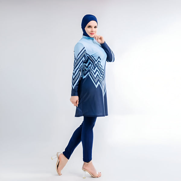 Une femme portant un maillot de bain islamique bleu et blanc avec un hijab assorti. Le maillot de bain a un motif géométrique et est long jusqu'aux genoux. La femme porte également des talons hauts transparents.