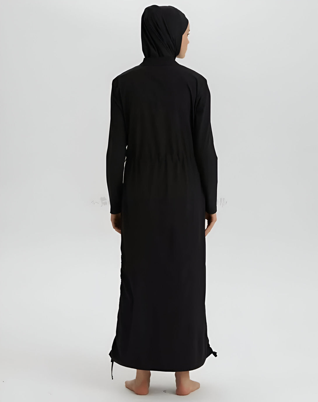 Une femme portant une robe de bain noire musulmane à manches longues avec une capuche. La robe est ample et couvre le corps de la cheville aux épaules. La robe est idéale pour la natation et les activités aquatiques.