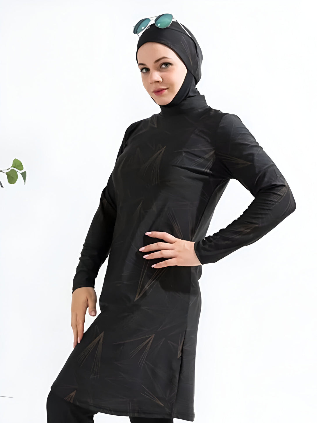 Une femme portant un maillot de bain musulman noir à imprimé doré et des lunettes de soleil.