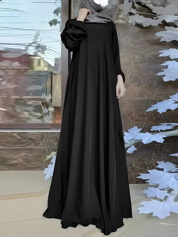 Une femme portant une longue robe noire ample, un hijab gris et des manches bouffantes. La robe est de style musulman et est parfaite pour les occasions spéciales.