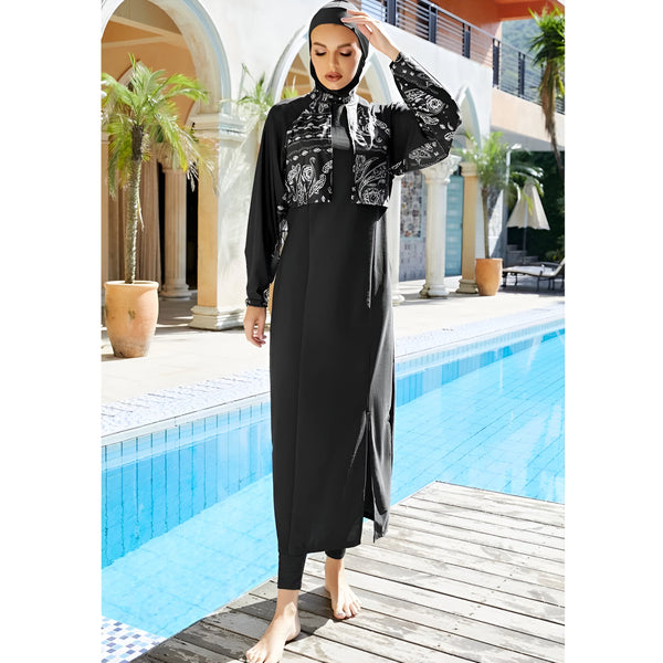 Une femme portant un maillot de bain musulman noir avec un imprimé blanc à motifs paisley, debout près d'une piscine.