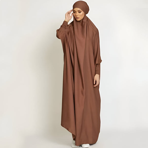 Une femme portant une abaya marron, un vêtement musulman long et ample, avec un hijab assorti.