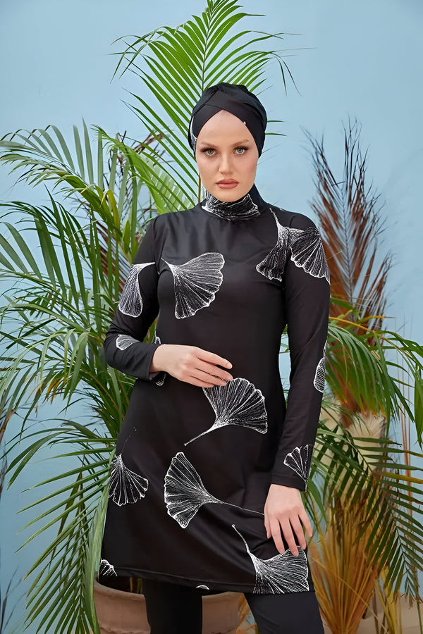 Une femme portant un maillot de bain musulman noir avec un motif de feuilles blanches.
