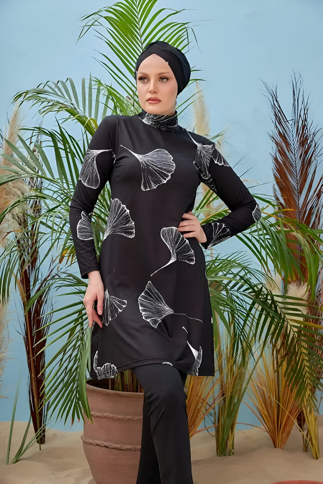 Une femme portant un maillot de bain musulman noir à motifs blancs de feuilles.
