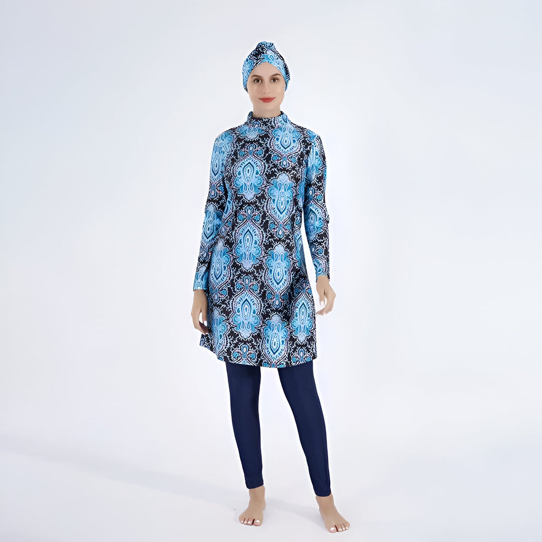 Une femme portant un maillot de bain musulman bleu et noir à motifs.  Le maillot de bain est composé d'une tunique à manches longues et d'un pantalon long. La femme porte également un hijab assorti.