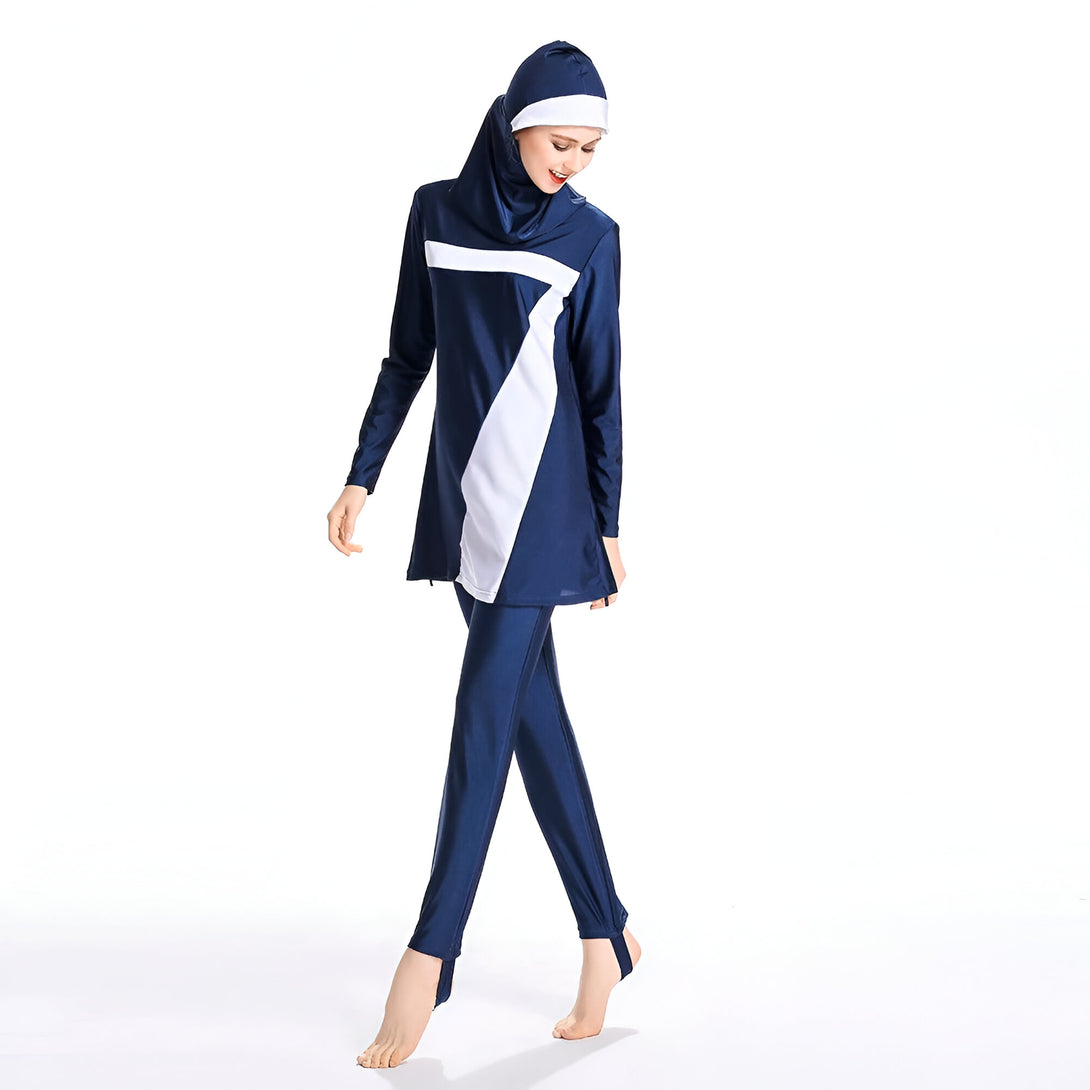 Une femme portant un maillot de bain musulman bleu marine avec des détails blancs. Le maillot de bain comprend un hijab, une tunique à manches longues et un pantalon.