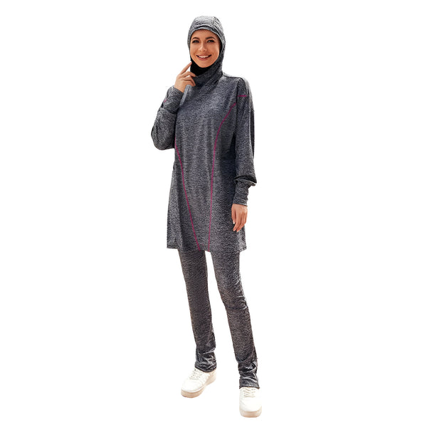 Une femme portant un ensemble de vêtements de bain musulmans gris avec des détails roses. Elle porte un hijab assorti et sourit à la caméra.