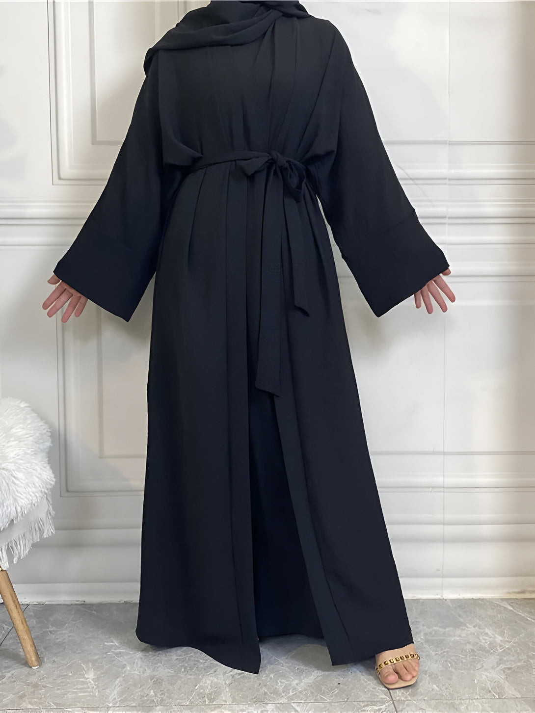 Une femme portant une abaya noire élégante avec une ceinture et des manches longues. L'abaya est conçue pour un look élégant et moderne.