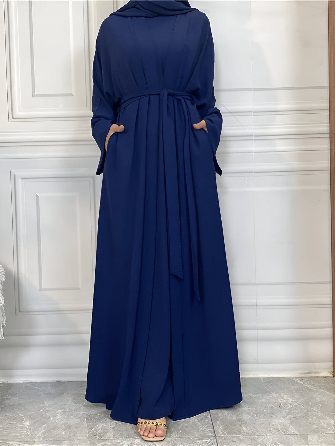 Une robe longue bleue marine avec une ceinture, parfaite pour les occasions spéciales. La robe est conçue pour un look élégant et moderne. Elle est faite d'un tissu léger et confortable, ce qui la rend idéale pour les jours chauds.