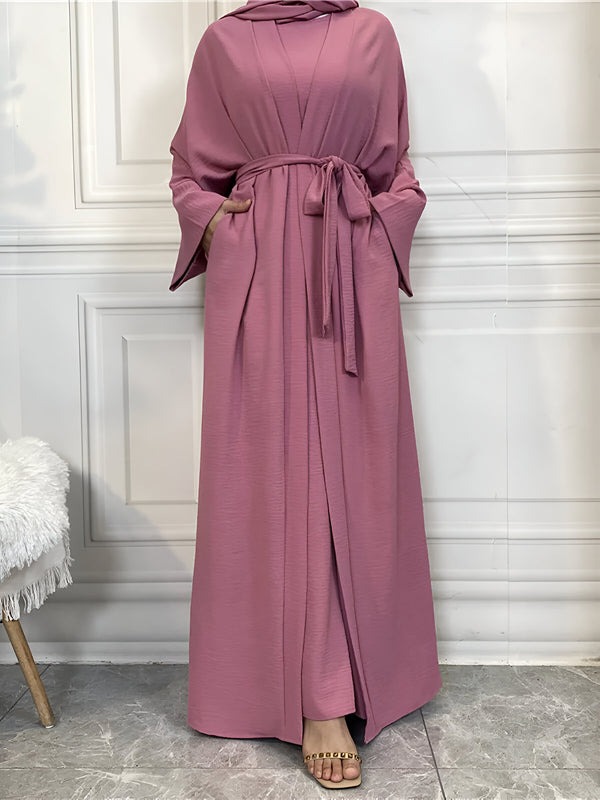 Robe longue rose pour femmes musulmanes avec ceinture et manches longues.  Parfait pour les occasions spéciales et le quotidien.