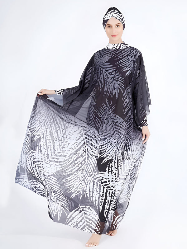 Une femme portant une robe de plage musulmane noire et blanche avec un imprimé de feuilles de palmier. La robe est en tissu transparent et a des manches longues. La femme porte également un foulard en tissu noir et blanc sur la tête.