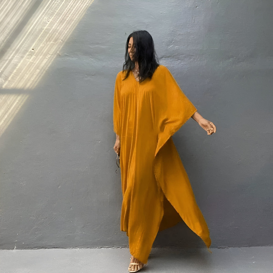 Une femme porte une longue robe jaune moulante à manches longues. La robe est ample et fluide, avec une coupe ample. Elle est parfaite pour les occasions décontractées ou formelles.