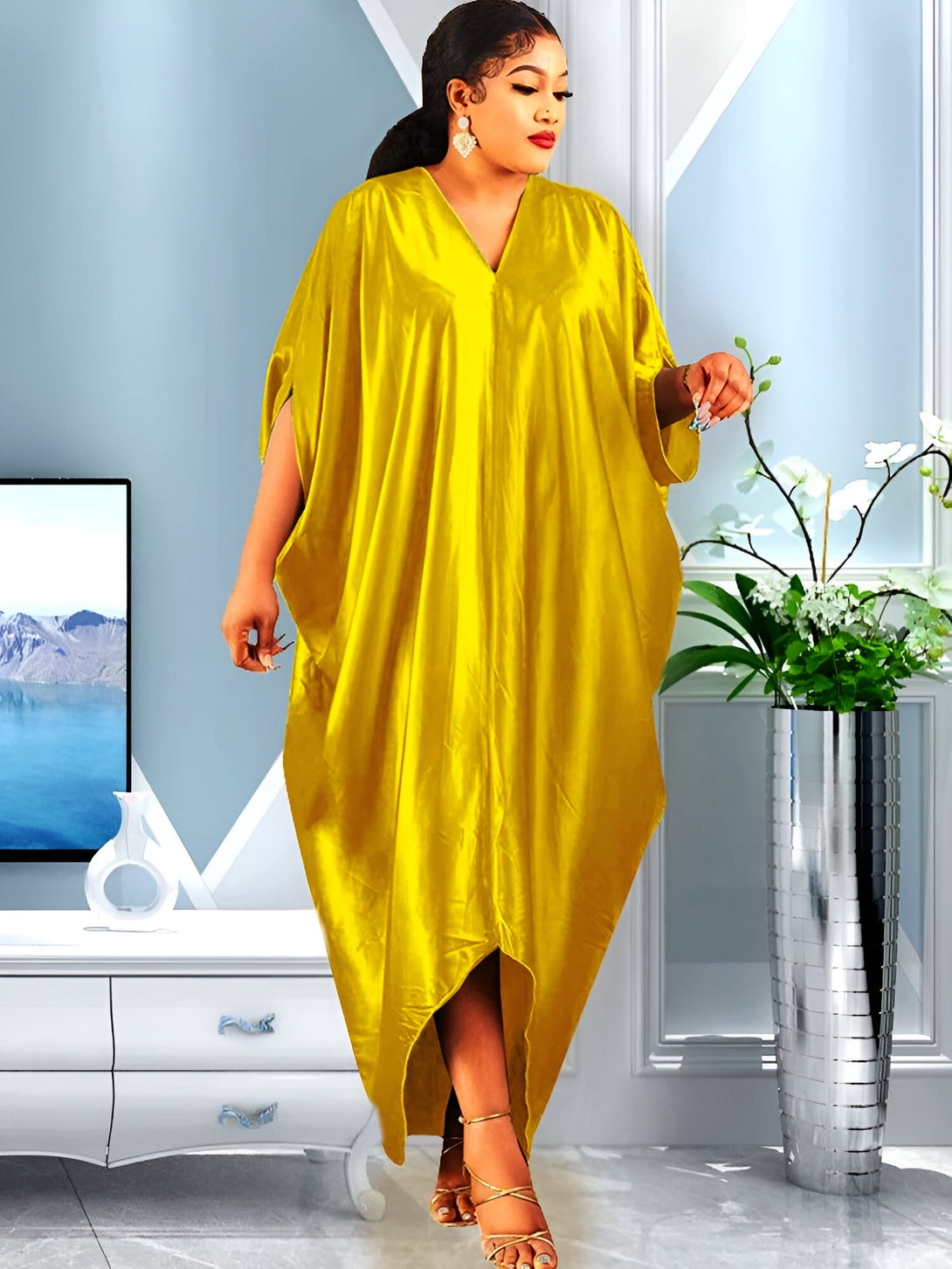 Une femme porte une longue robe jaune en satin avec un col en V. La robe est ample et a des manches courtes. La robe est parfaite pour les occasions spéciales ou pour un look décontracté et élégant.