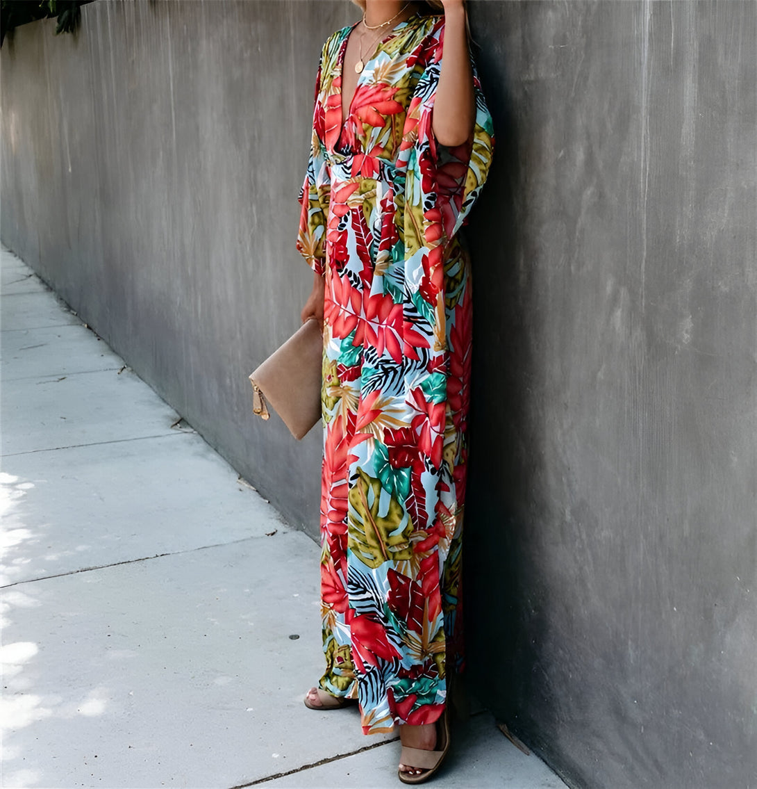 Une femme portant une longue robe à imprimé floral, parfaite pour les occasions décontractées. La robe est de couleur rouge, bleue et verte et présente un motif floral tropical.