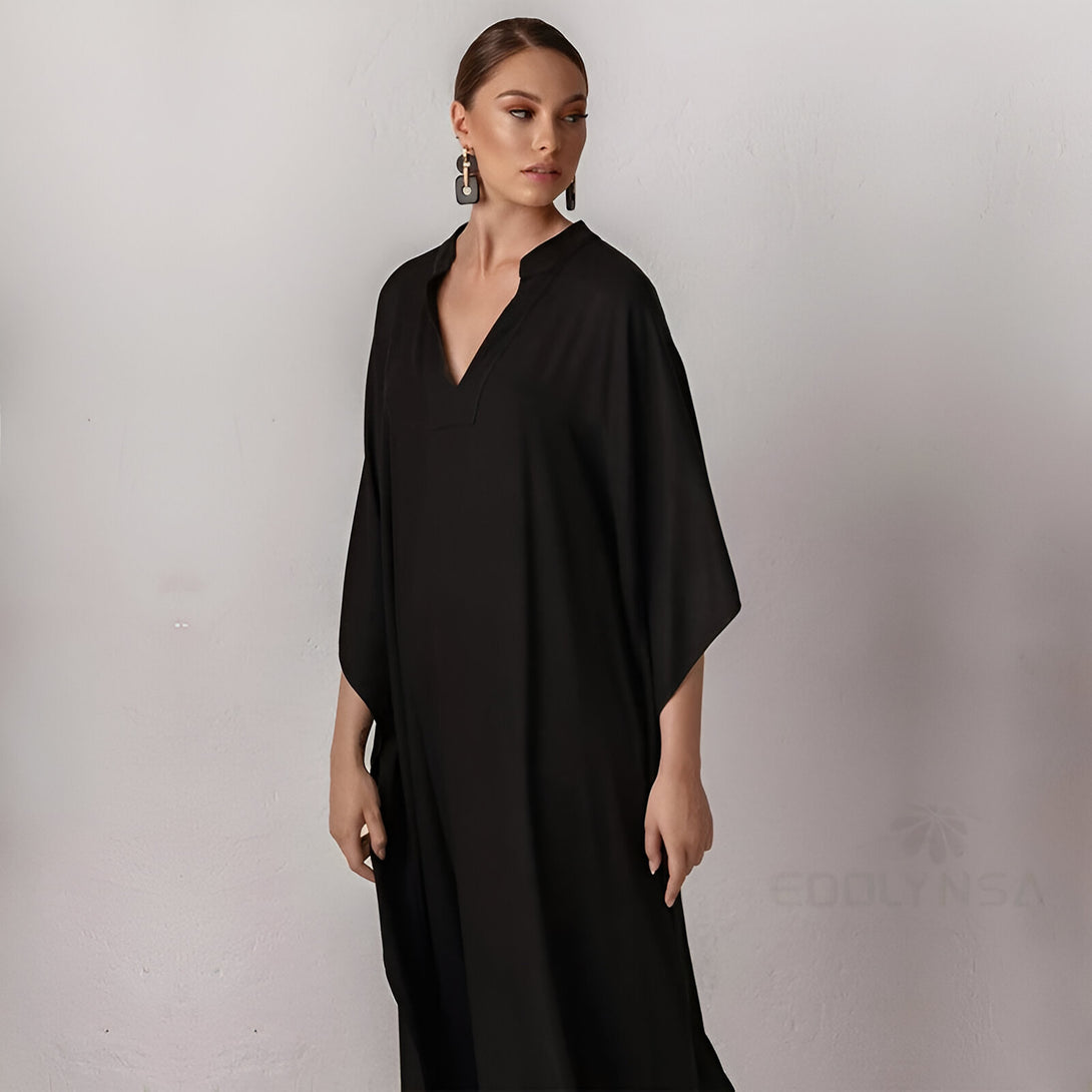 Une femme portant une longue robe noire ample avec un col en V. La robe est idéale pour les occasions spéciales ou le quotidien.