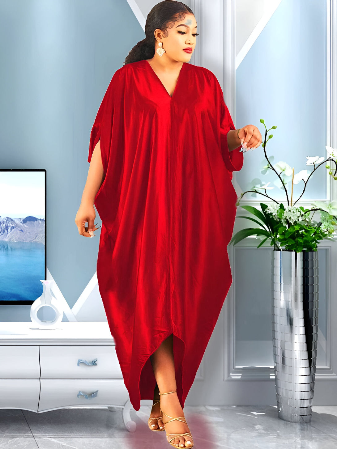 Une femme porte une robe rouge ample et élégante avec un col en V. La robe est parfaite pour les occasions spéciales et les fêtes. Elle est élégante et confortable, et elle vous permettra de vous sentir belle et à l'aise.