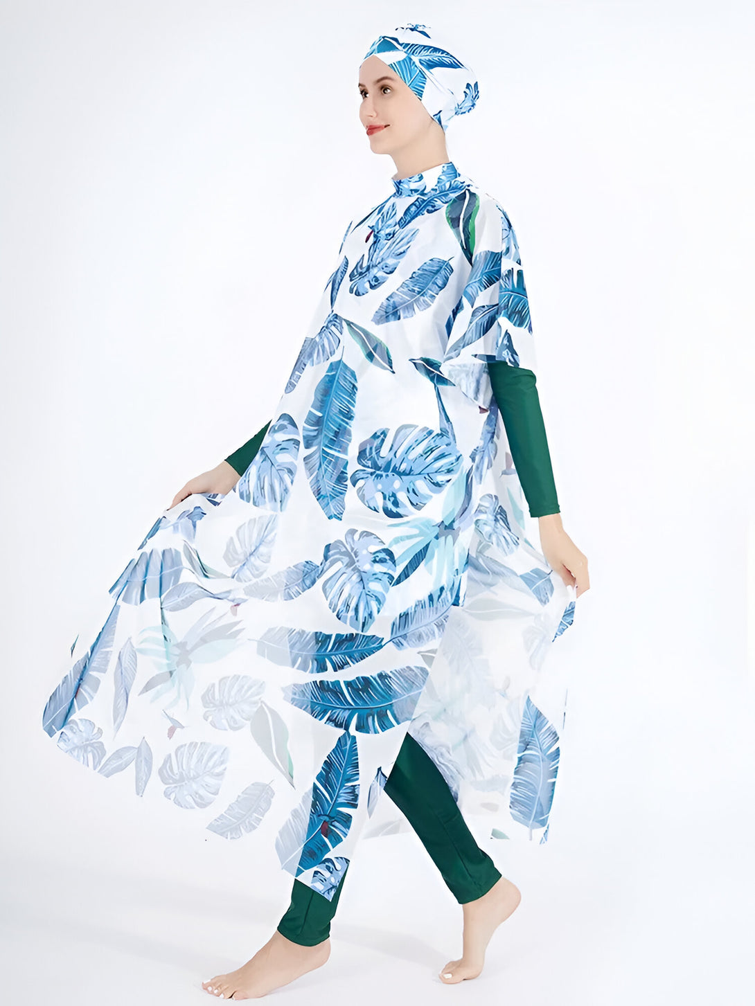 Une femme portant un maillot de bain musulman avec un motif de feuilles bleues sur fond blanc. Elle porte un hijab assorti.